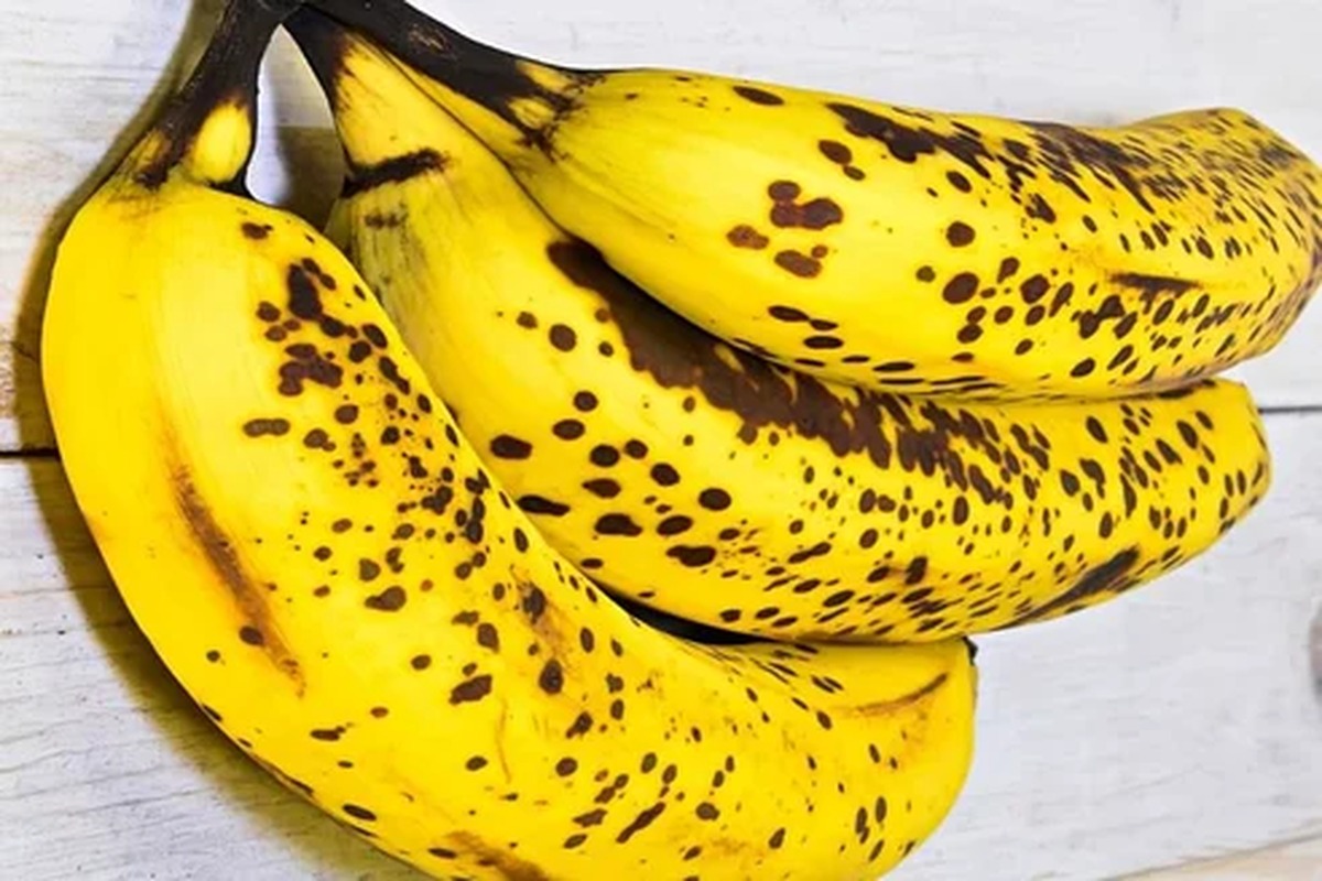 Un casco di banane mature appoggiato su una superficie chiara